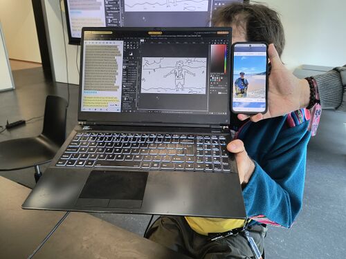 Two people posing with a laptop and a smartphone, showing respectively a drawing and a photo of someone on the beach