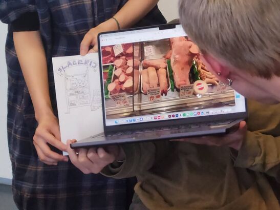Picture of a drawing and a photo of a slagerij, with the head of someone in the forefront looking at it.