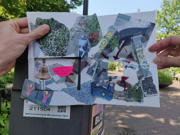 A sticker on a thrashcan in a park with a map put over it in such a way that the gap in the map lines up with the sticker